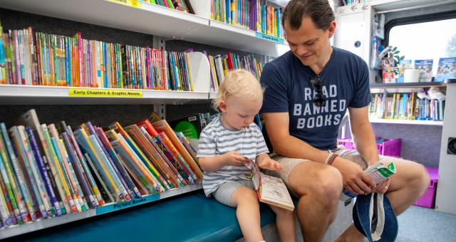 A toddler and his dad look at books on the Bookmobile during Library Night at Victory Field.