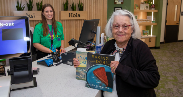 A smiling borrower shows her two checked out books.