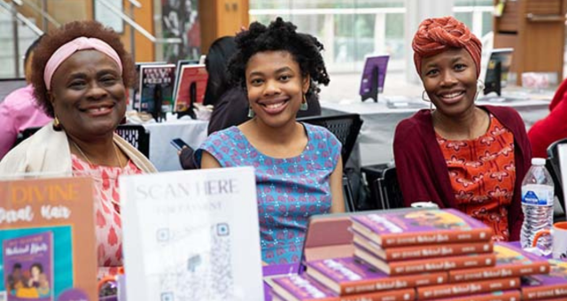 Three authors at the CBLC Book Fest & Juneteenth Celebration sit at a table with their books on display.