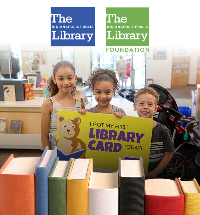 Three smiling children holding a sign that says I got my first library card today!