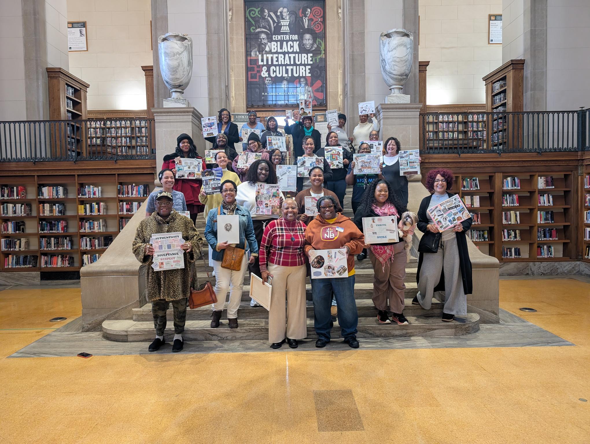 Large group shot of the participants of the She Leads Legacy: New Year, New Visions event on January 17, 2026 standing on the steps outside the entrance of the Center for Black Literature & Culture holding the vision boards they created.