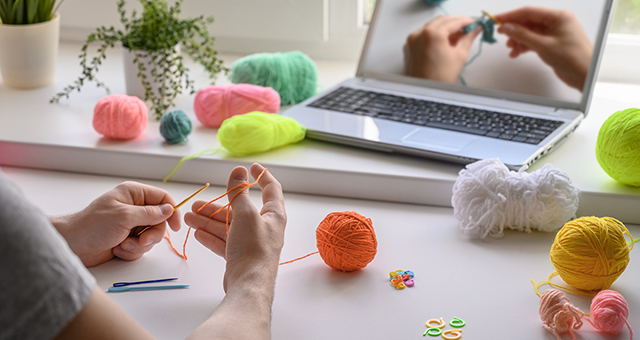 Person learning to knit from an online tutorial.