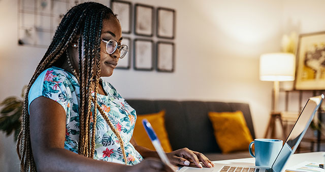 Woman working on a laptop sitting at a desk.