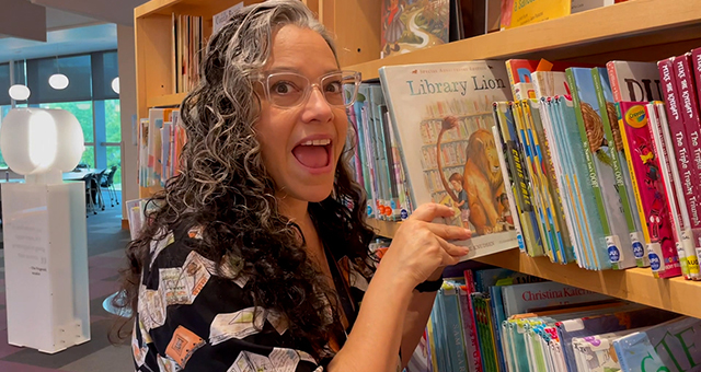 Librarian pulling a picture book from the shelf.