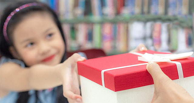 child handing someone a gift at the library