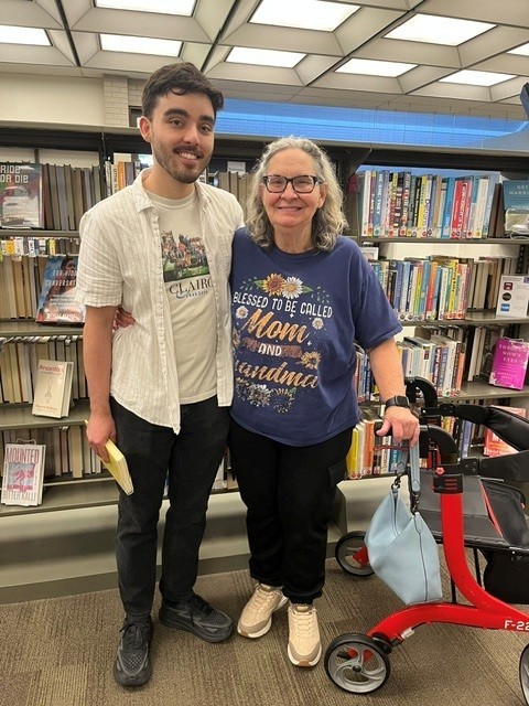 A tall boy and his mother stand in front of bookshelves at the Southport Branch