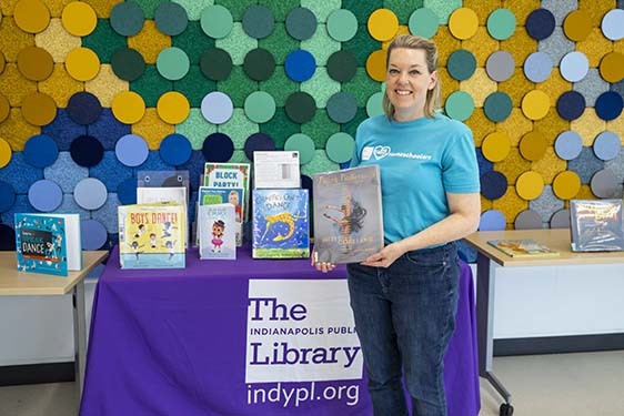 Librarian standing beside a table displaying books about dancing.