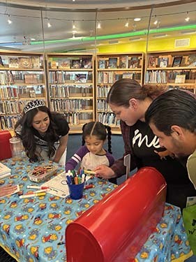 A young child works on a letter to put in the big red mailbox.