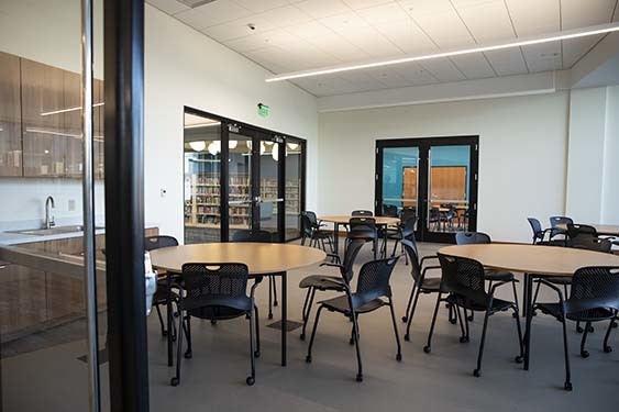 A meeting room with three round tables and numerous chairs.