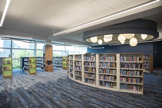 A curved book case filled with children's books under numberous warm lights.