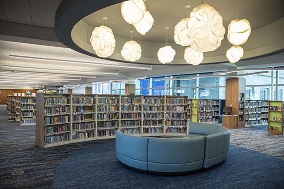 A large curved blue sofa in front of a curved book case at Kid Central.