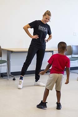 A dance instructor teaching a young child to balance on one foot.