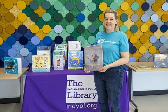 A librarian standing with a book display of titles about dance for children.