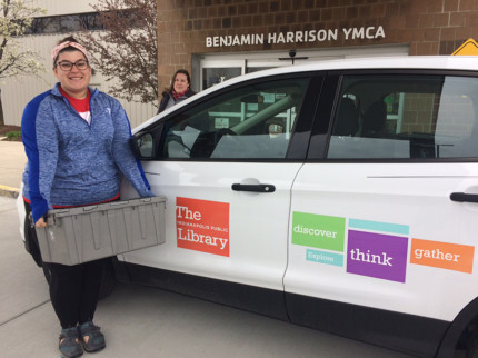 “Ariana Adams (foreground) of the Benjamin Harrison YMCA received the first delivery of materials from the Library’s Outreach Services Manager Maggie Ward that will help young children of essential workers with their reading and early literacy skills.”
